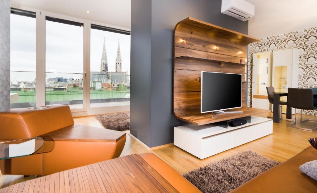 een woonkamer met een flatscreen-tv op een standaard bij Abieshomes Serviced Apartments - Votivpark in Wenen