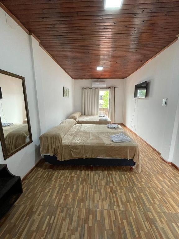 een slaapkamer met twee bedden en een houten plafond bij Hotel Don Raul in Puerto Iguazú