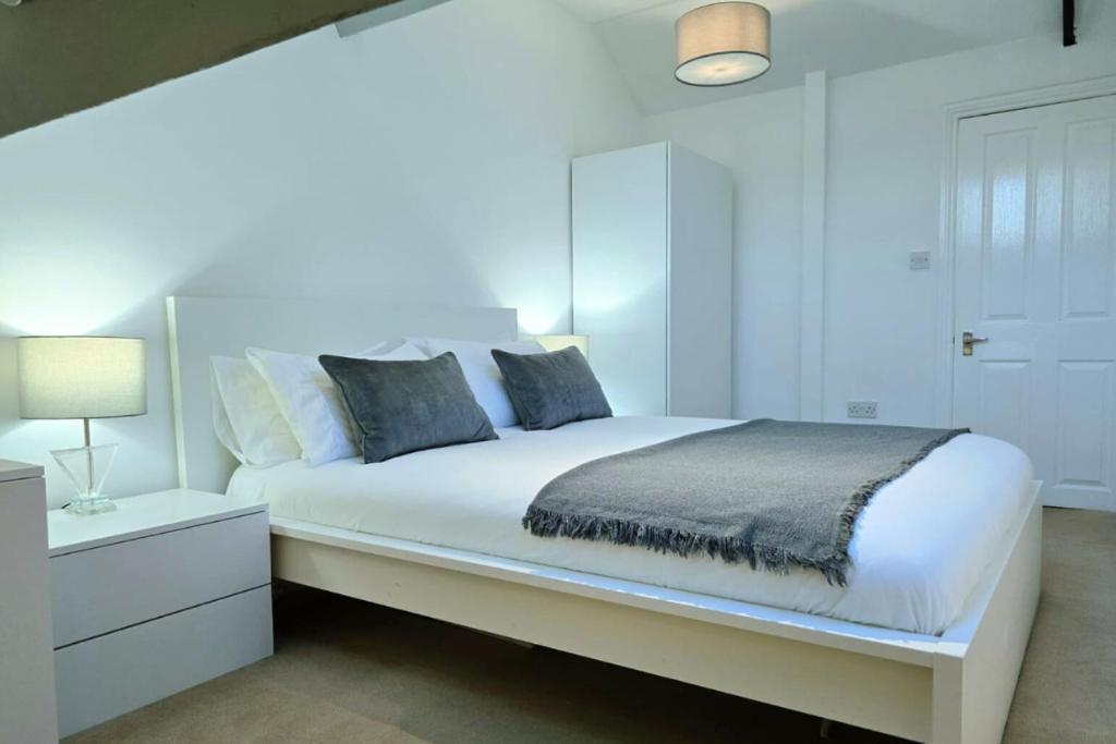 a white bedroom with a large bed with a night stand at King Size City Centre En Suite Room with Parking in Preston