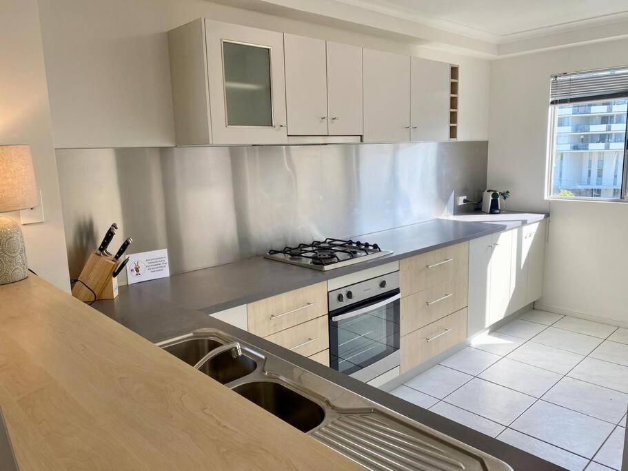 a kitchen with white cabinets and a stove top oven at Good Vibes Only on Stanley in Townsville
