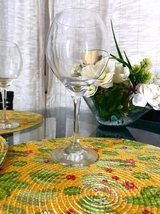 a wine glass sitting on a table with a vase of flowers at Porto Allegra in Cabo Frio