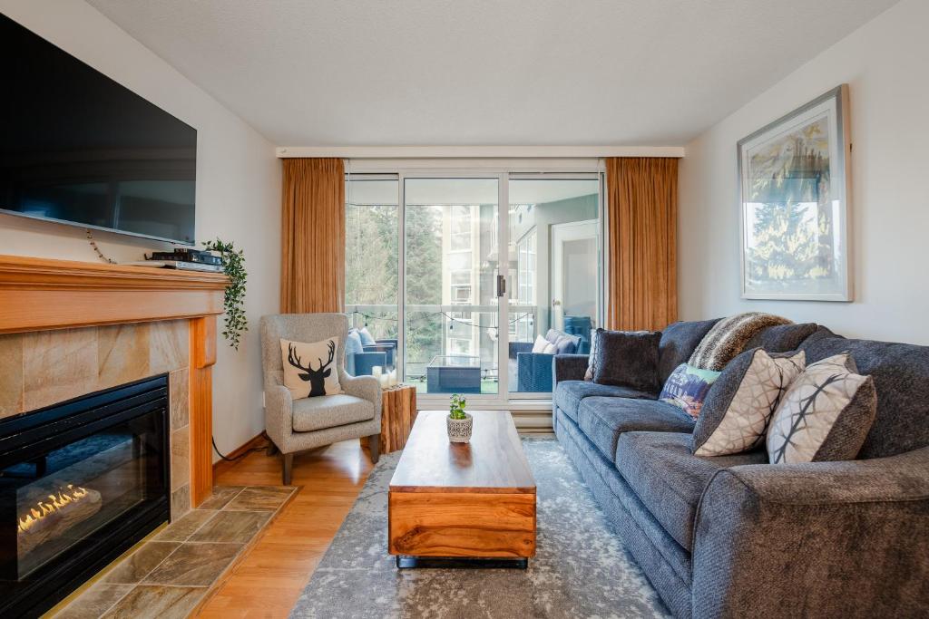 a living room with a couch and a fireplace at 2BR plus den Ski in Ski out Condo with Pool and Hot Tub by Harmony Whistler in Whistler