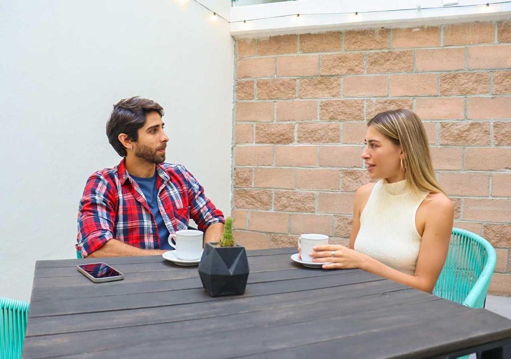 Two guests seated at an outdoor table with coffee cups.