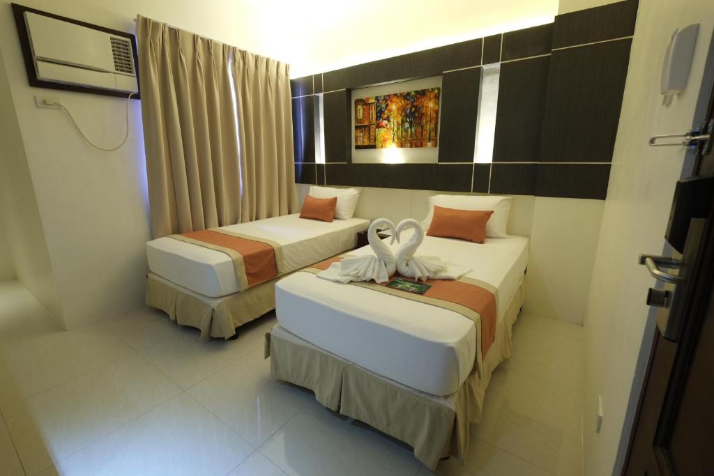 two beds in a hotel room with a room at Southpole Central Hotel in Cebu City