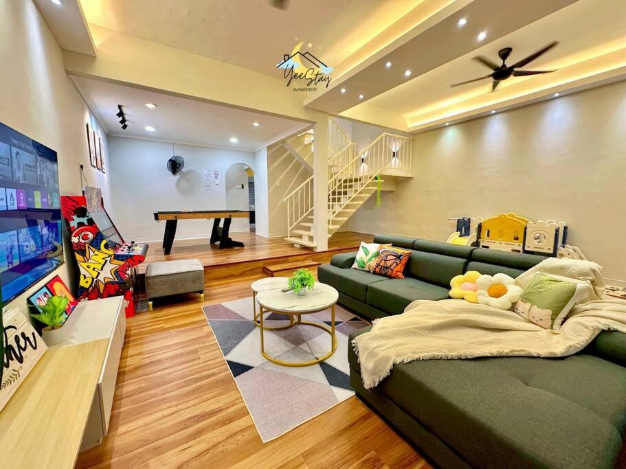 a living room with a green couch and a table at Kampung8 17pax Snooker Arcade in Melaka