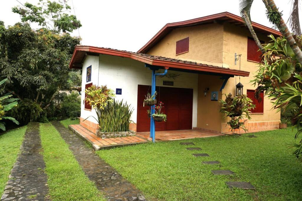 a small house with a red door and a yard at Casa Familiar y Naturaleza en Parcelación Privada in Amagá