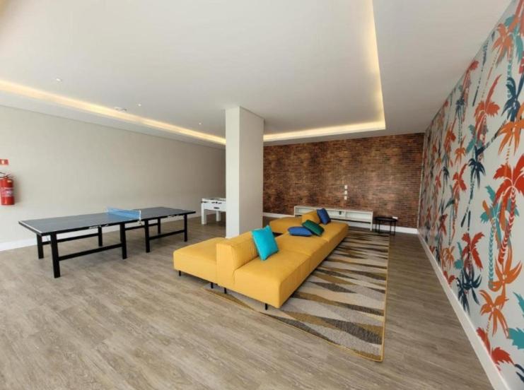 a living room with a yellow couch and a table at Apartamento Tulum Bertioga in Bertioga