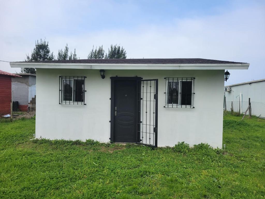 a small white house with a black door at Casa en El Pinar in Ciudad de la Costa