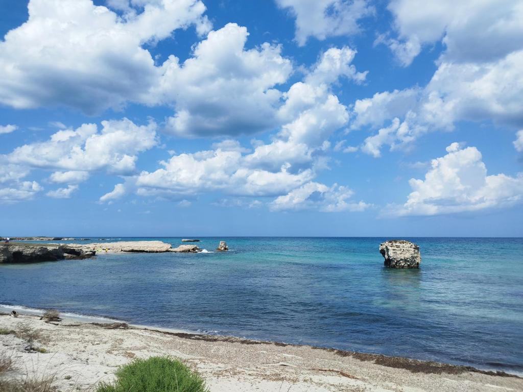 a beach with a rock in the water at Villetta Le Cesine in Torre Specchia Ruggeri