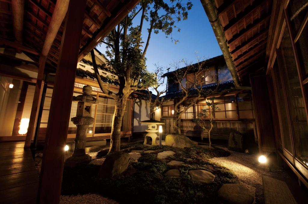 NIPPONIA Sasayama Castle Town Hotel في Sasayama: ساحة مبنى فيه شجرة وانوار