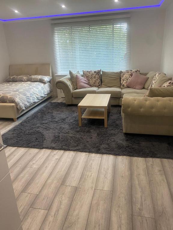 a living room with a couch and a coffee table at Lovely Modern studio flat with jacuzzi bath free parking in Stanwell