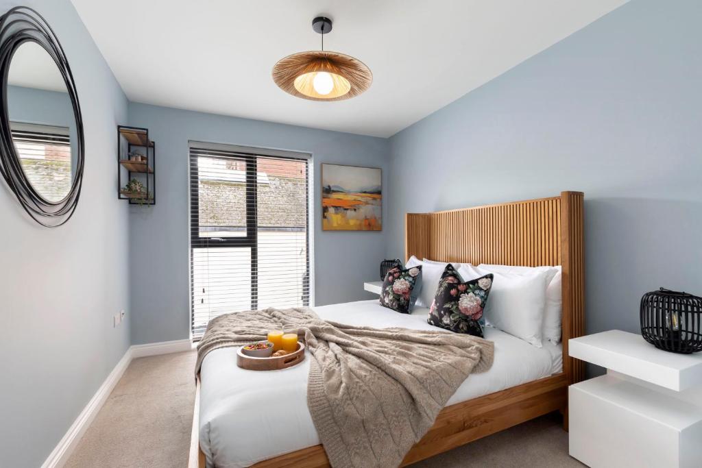 a bedroom with a bed with blue walls and a mirror at Elliot Oliver - Beautiful Two Bedroom Apartment With Parking in The Docks in Gloucester