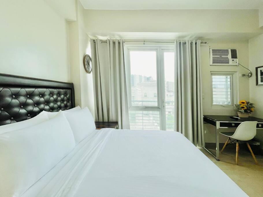une chambre avec un grand lit blanc et un bureau dans l'établissement 19 Cityscape Views, à Cari Mayor
