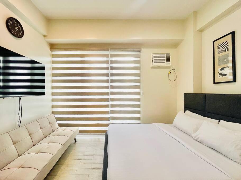 une chambre avec un lit blanc et un canapé dans l'établissement 20 Pool View Studio Bliss, à Cari Mayor