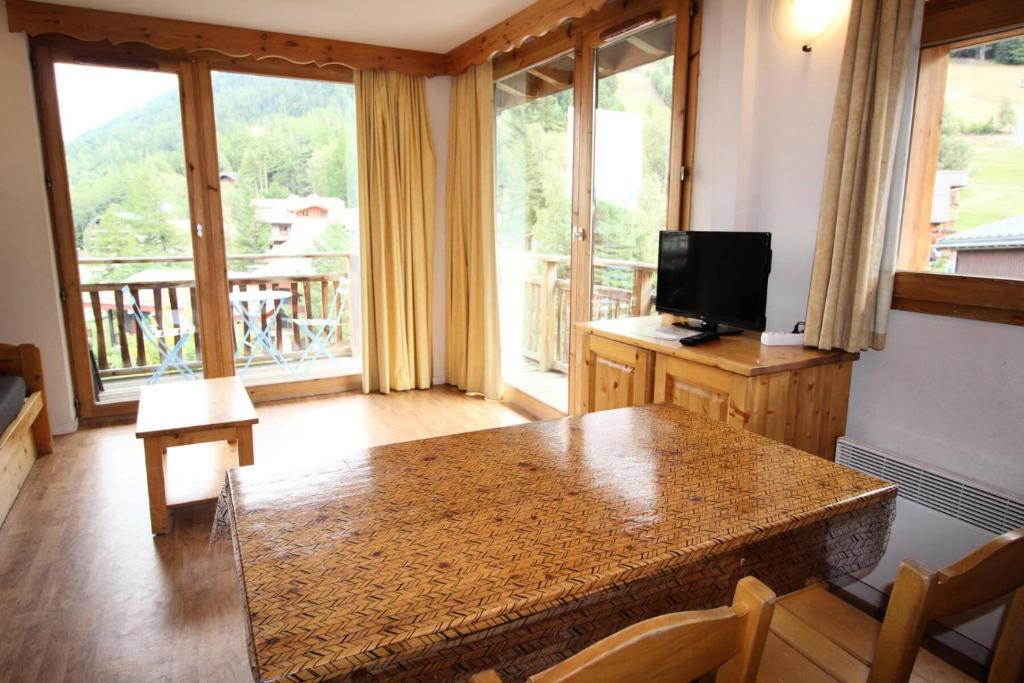- un salon avec une table et une télévision ainsi que quelques fenêtres dans l'établissement Chalets De La Vanoise - Les Chalets de la Vanoise-CV1202 MAE-4761, à Villarodin-Bourget