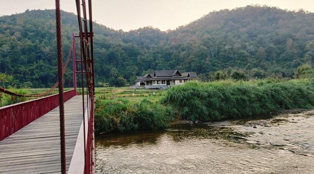 a bridge over a river with a house in the background at Villa Mae Hong Son in Mae Hong Son