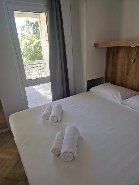 a bedroom with a bed with towels on it at Mobile homes Jezera Lovišća Premium in Jezera
