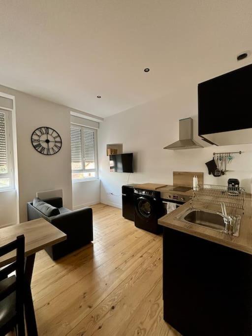 une cuisine avec une table et une horloge au mur dans l'établissement Studio fonctionnel, centre ville, rénové 205, à Saint-Étienne