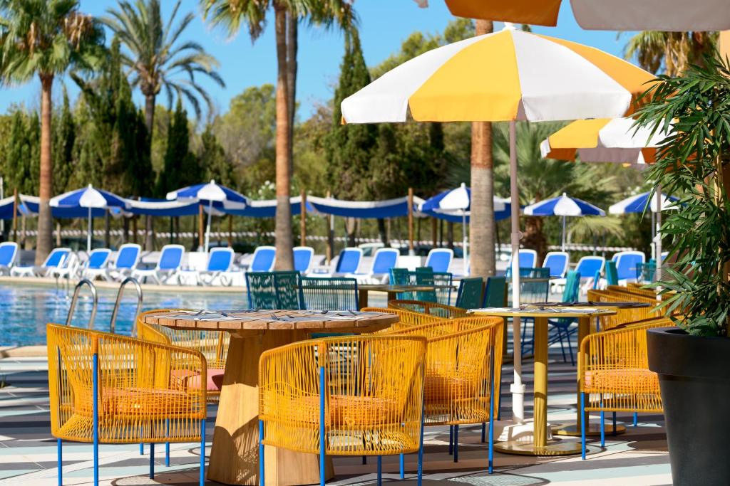 un gruppo di tavoli e sedie con ombrelloni e una piscina di tent Mojito Suites a Magaluf