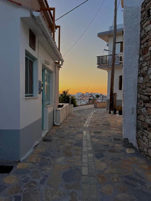 an empty alleyway between two buildings with the sunset in the background at Sunrise in Kokkari
