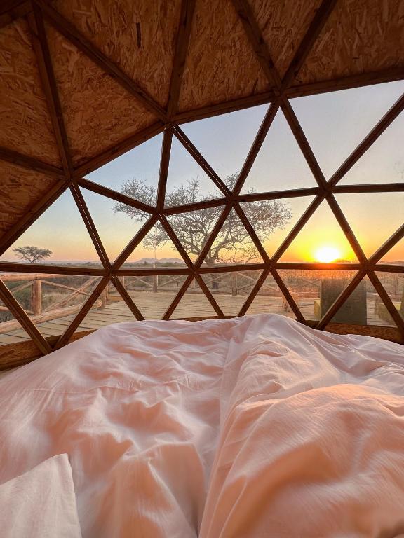 a bed in a tent with the sunset in the background at Kuoom Serengeti in Robanda