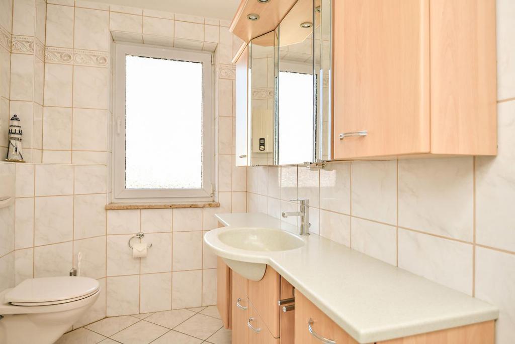 a bathroom with a sink and a toilet and a mirror at Haus Kehrwieder Leuchtturm in Grömitz