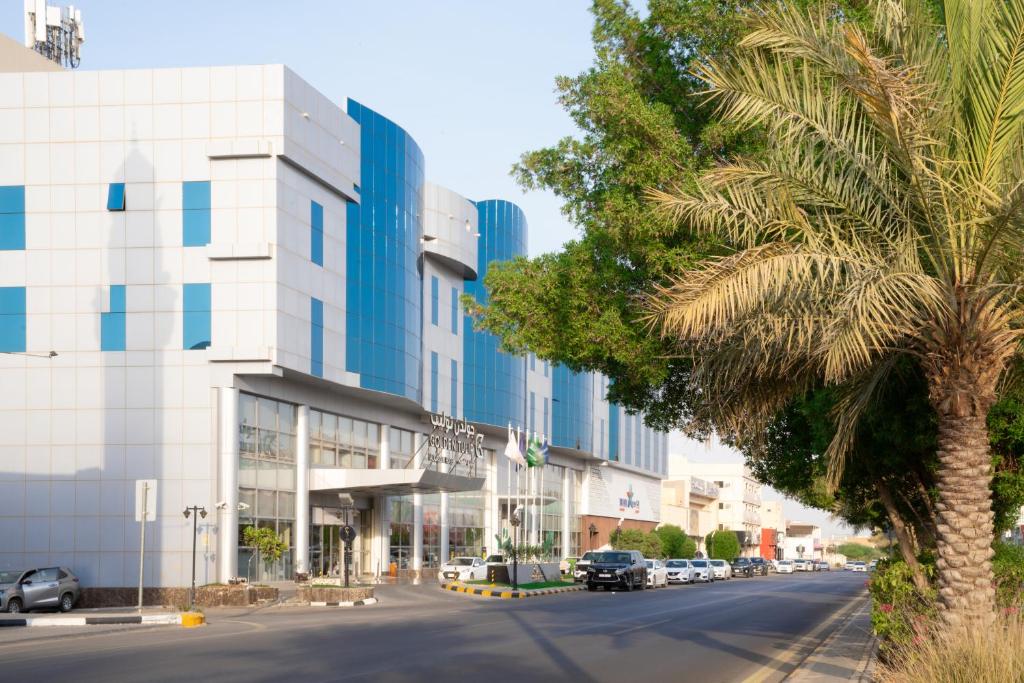 a palm tree in front of a building at Golden Tulip Hotel Buraidah Al Qassim in Buraydah