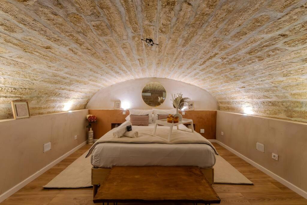 Ce lit se trouve dans un dortoir doté d'un plafond en pierre. dans l'établissement La Suite Eximia avec Patio - Parking Souterrain Inclus - Centre Historique, à Montpellier