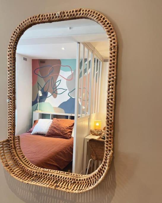 - un miroir en osier sur un mur dans une chambre dans l'établissement Le studio du Marché, hyper centre, à La Rochelle