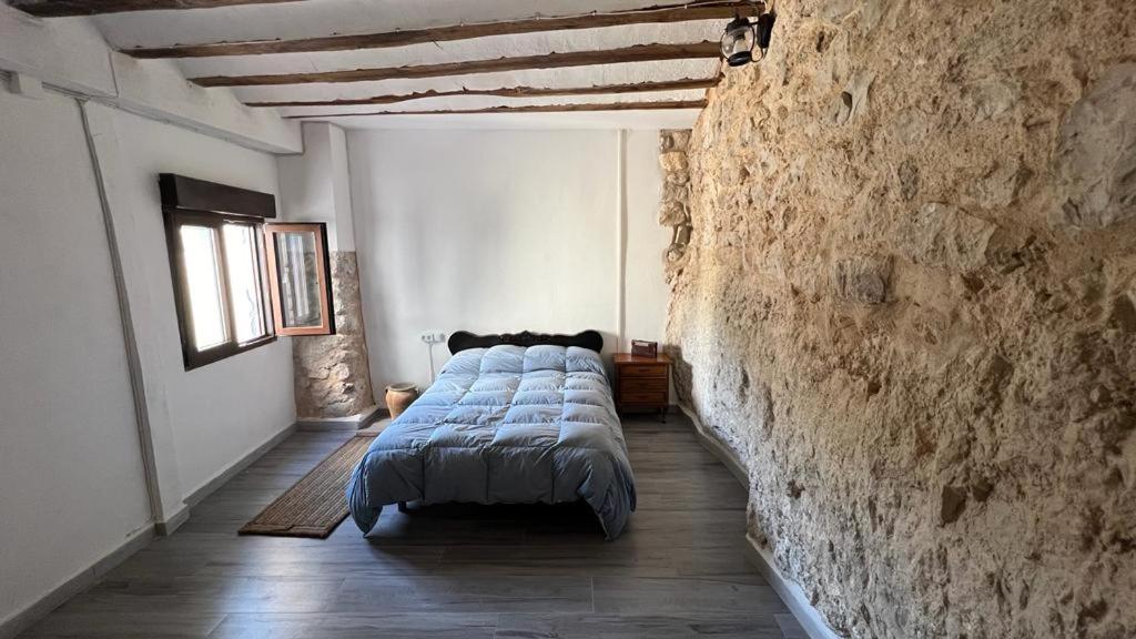 a bedroom with a bed and a stone wall at Casa Cueva Toni in Alcalá del Júcar