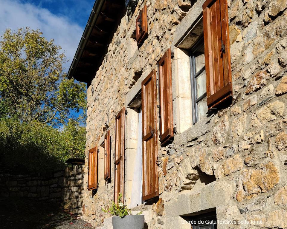 - un bâtiment en pierre avec des fenêtres en bois dans l'établissement Le Gatu by Les Gîtes de la Jonte, à Gatuzières