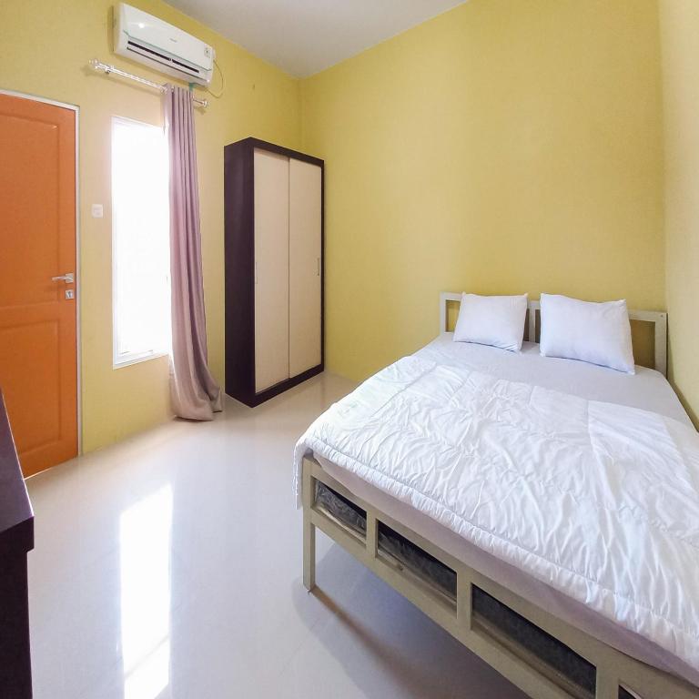 une chambre avec un grand lit aux murs jaunes dans l'établissement FARAH Homestay Syariah Mitra RedDoorz, à Pekanbaru