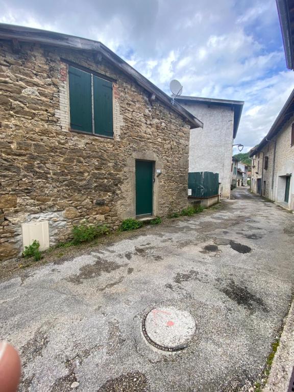 - un bâtiment en pierre avec une porte verte dans une rue dans l'établissement Petite maison de charme, à Saint-Rambert-en-Bugey