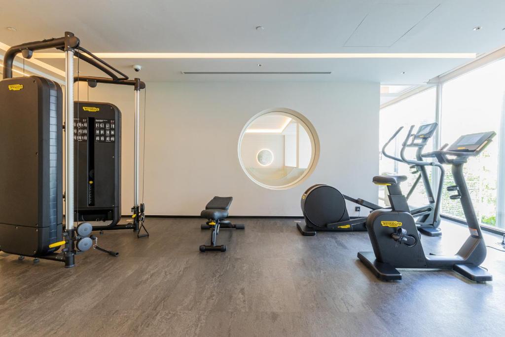 A bright fitness room with a cable machine, cardio equipment, and a bench.