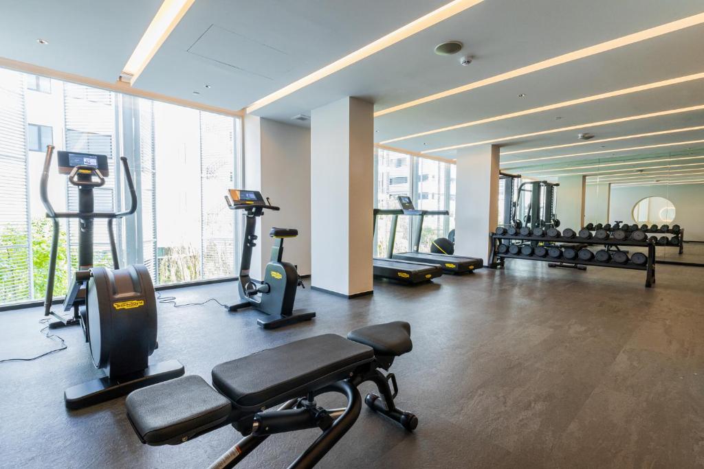 A spacious cardio and strength room with bikes, treadmills, benches, and mirrored dumbbell racks.