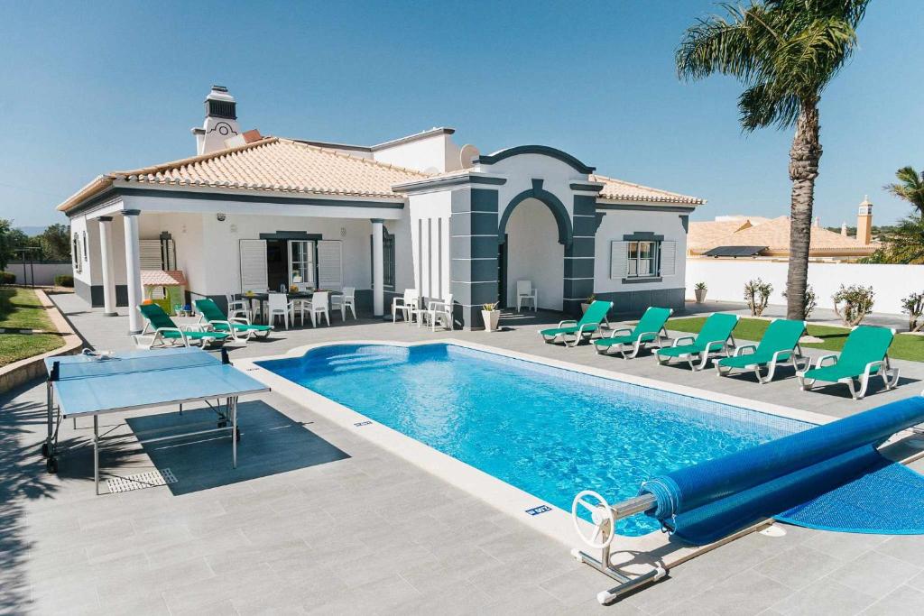 ein Swimmingpool mit Stühlen und ein Haus in der Unterkunft Villa Jorge by Ecovillas Albufeira in Galé