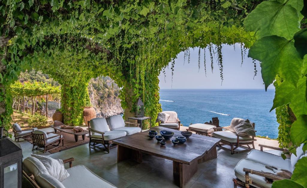 Una sala de estar con una mesa y sillas y el océano. en Villa Limonaia, en Maiori