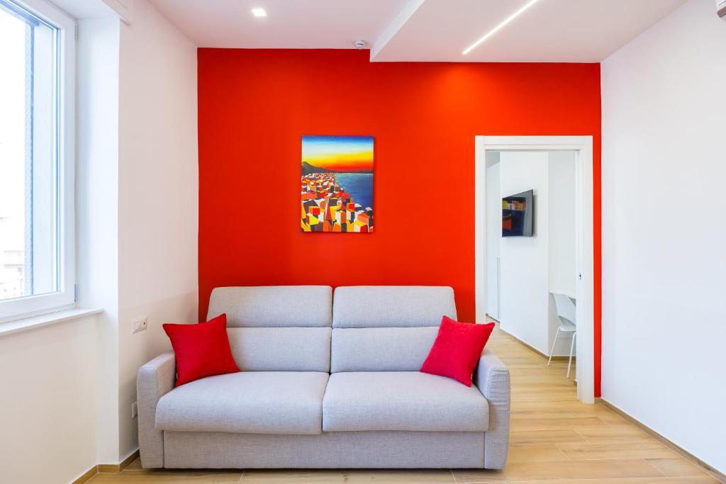 a living room with a couch against a red wall at NUOVO appartamento nel cuore di Napoli AT TWENTY ONE - CORAL in Naples