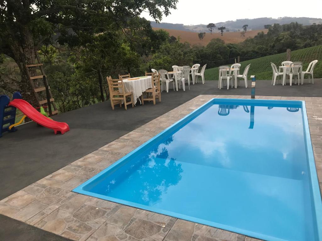una piscina con tavolo e sedie e un parco giochi di Sítio Recanto do Pardal a Santa Rita de Caldas