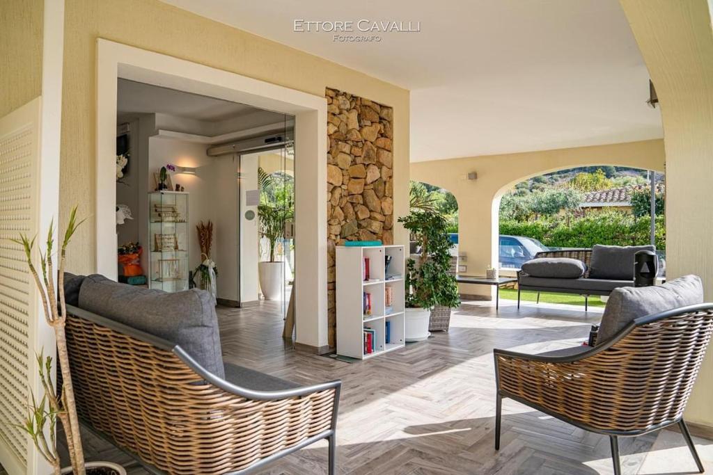 a living room with two chairs and a stone wall at Suimi's Hotel in Villasimius