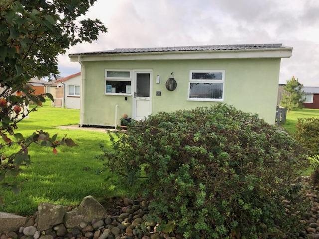 a small green house with a bush in front of it at Chalet 147 South Shore Bridlington in Bessingby