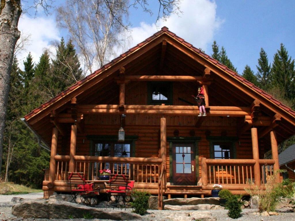 a log cabin with a person standing on the porch at Holiday home Placzek in Schierke