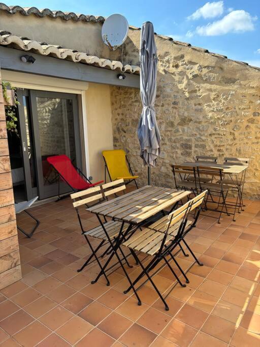 un patio avec tables, chaises et un parasol dans l'établissement La Montée du Château, à Grignan
