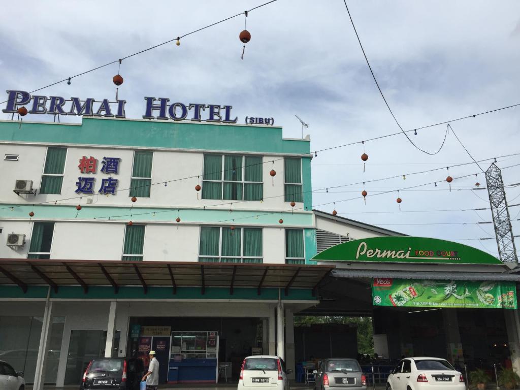 a hotel with cars parked in front of it at Permai Hotel in Sibu