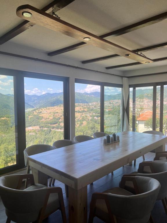 una gran mesa y sillas en una habitación con ventanas en ВИЛА ЯНА Villa Yana, en Presoka