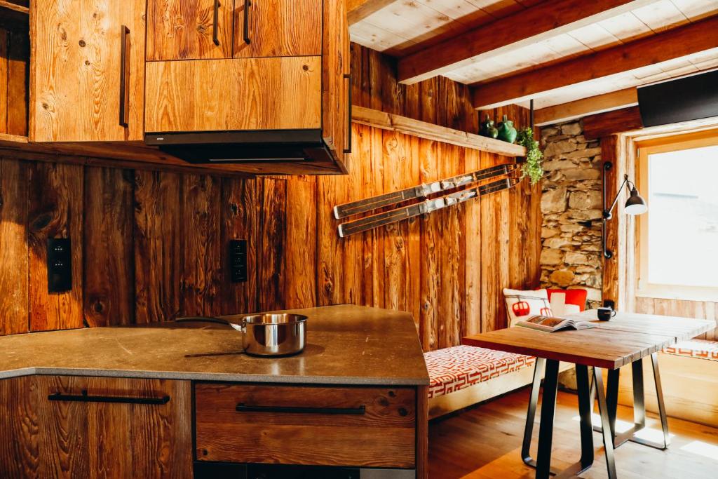 eine Küche mit Holzwänden und einer Theke und einem Tisch in der Unterkunft Chalet des Amis by Lodji in Saint-Marcel
