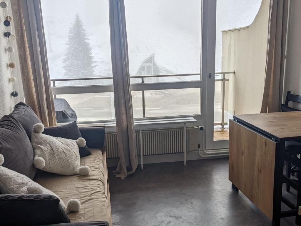 un salon avec un canapé et une grande fenêtre dans l'établissement Studio cabine cosy au pied des pistes avec balcon - FR-1-557-115, à Les Adrets