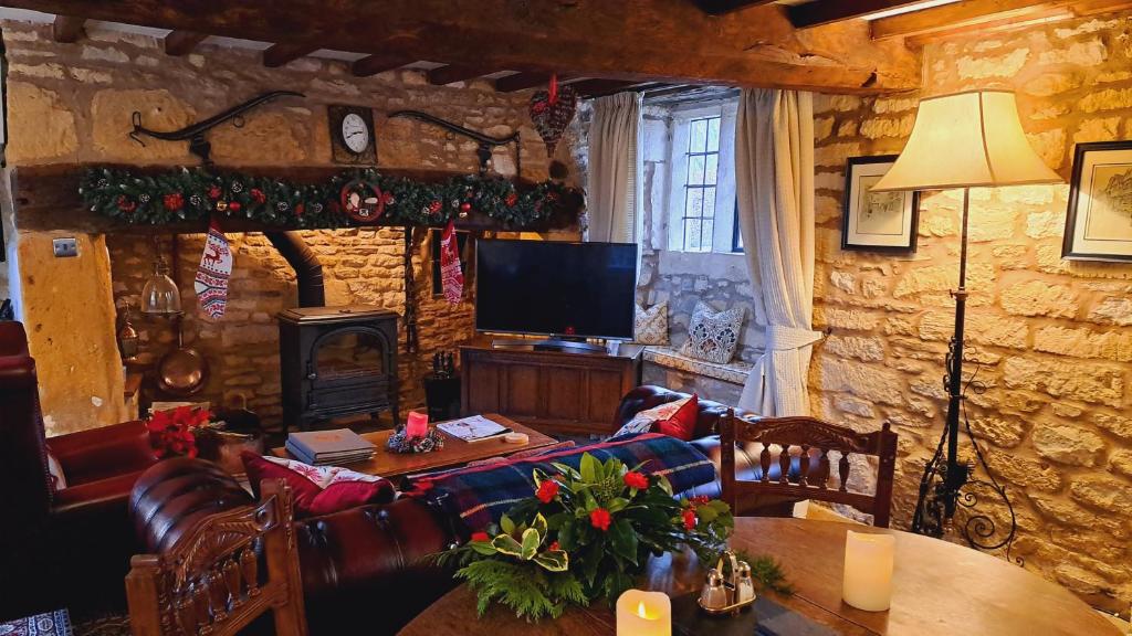a living room with a couch and a table at Graziers Cottage - character Cotswold cottage with inglenook, parking and pub nearby in Cheltenham