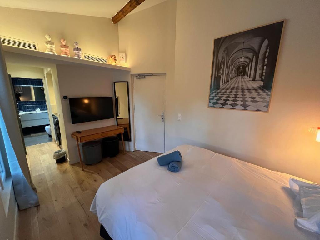 une chambre avec un lit blanc et une télévision à écran plat dans l'établissement Saint Jacques Versailles, à Paris