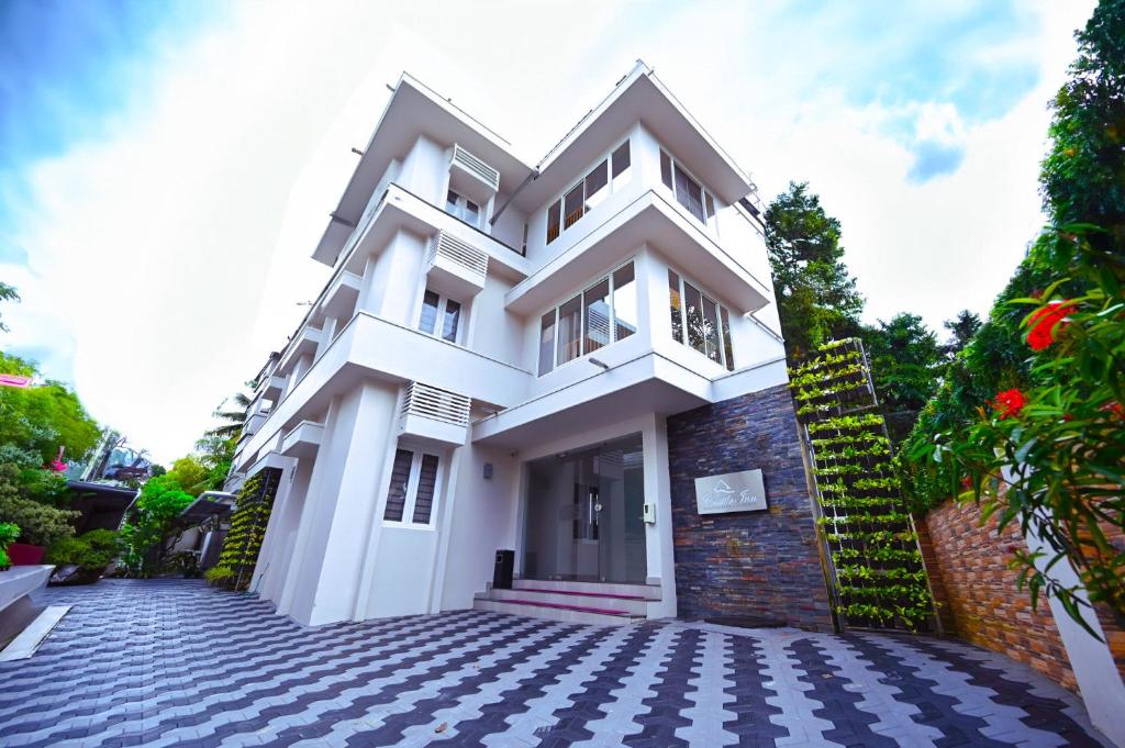 a white house with a cobblestone driveway at Castilo Inn Hotel Apartments in Cochin